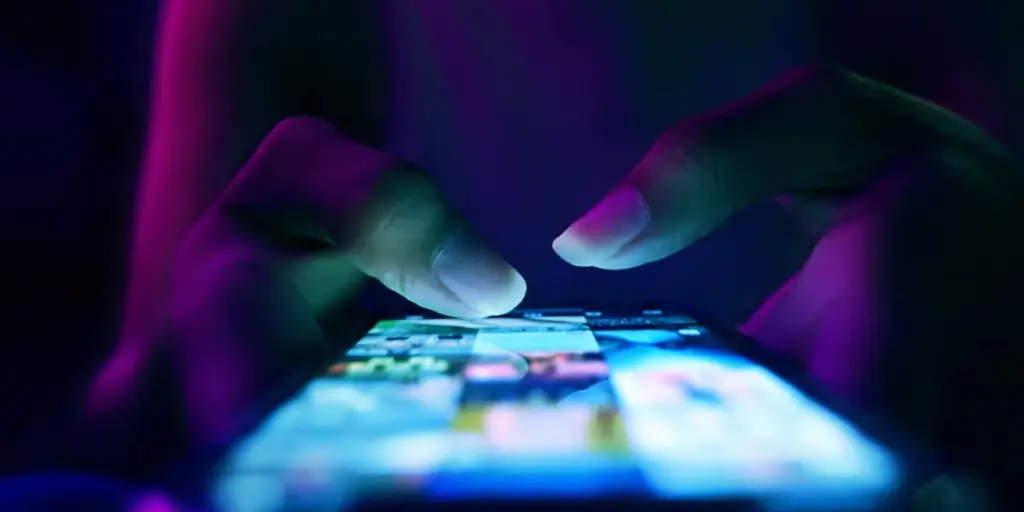 Close up of a person’s hands scrolling through a social media page on their phone.
