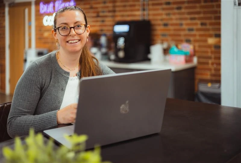 Charlotte Luff from PMW Communications sitting at desk with her laptop.