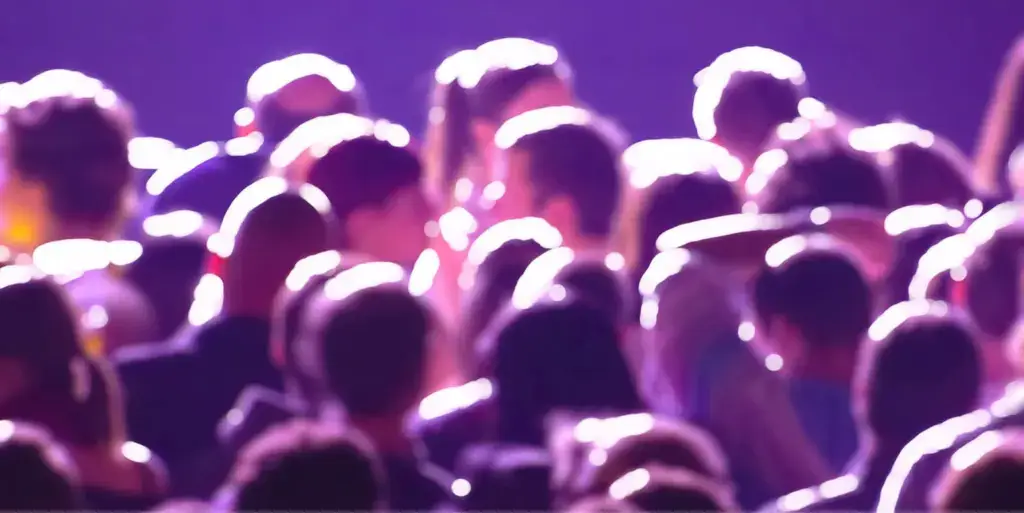 Blurred image of people in a room with a purple tinge.