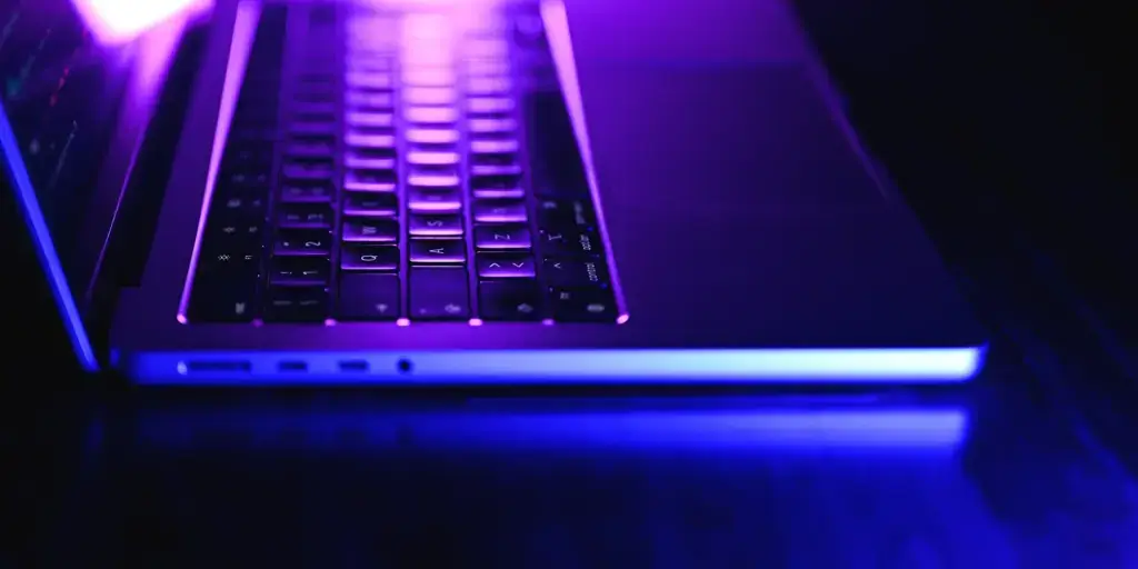 side view of a laptop keyword with a purple glow